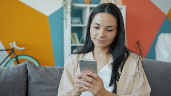 ai彼女 おすすめアプリ-ソファでスマートフォンを見ながらくつろぐ女性