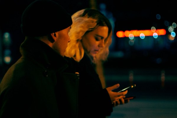 ai彼女 会話アプリ-夜の街灯の下でスマートフォンを見る様子
