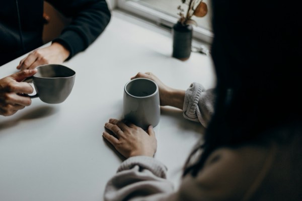 ai彼女 会話アプリ-テーブルで温かい飲み物を挟んで向き合う手元